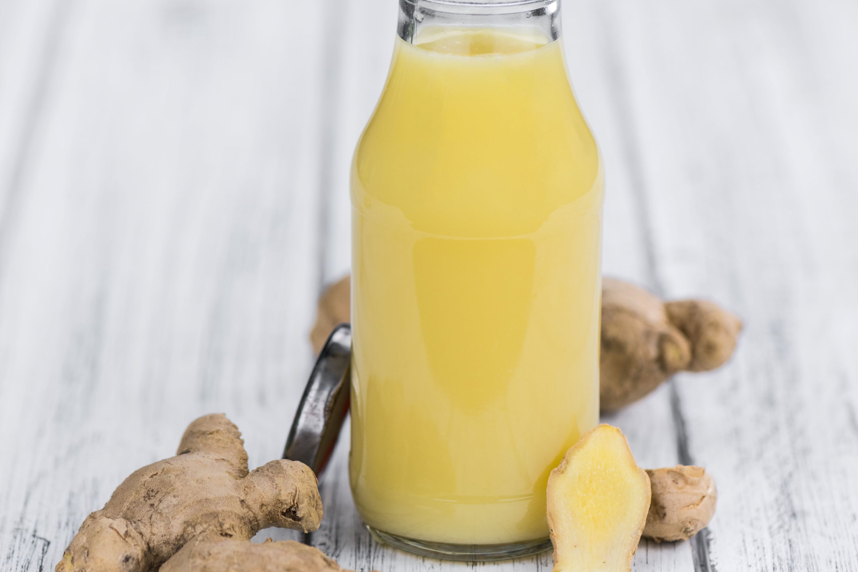 Saft für Ingwershots in einer kleinen Flaschen mit Ingwer auf dem Tisch