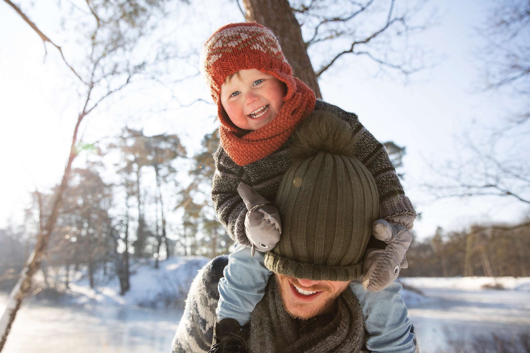Kleines Kind auf Schulter eines Mannes im Winter
